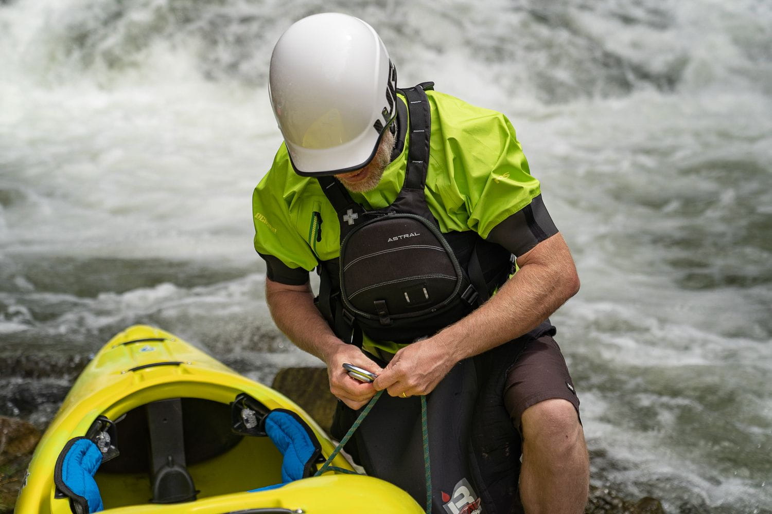 Kajakfahrer mit Astral GreenJacket Rettungsweste bei der Strömungsrettung am Wildwasser. Professionelle Rescue-Ausrüstung für Wasserrettung, Rafting, Kajaksport und Rettungseinsätze auf Fließgewässern.