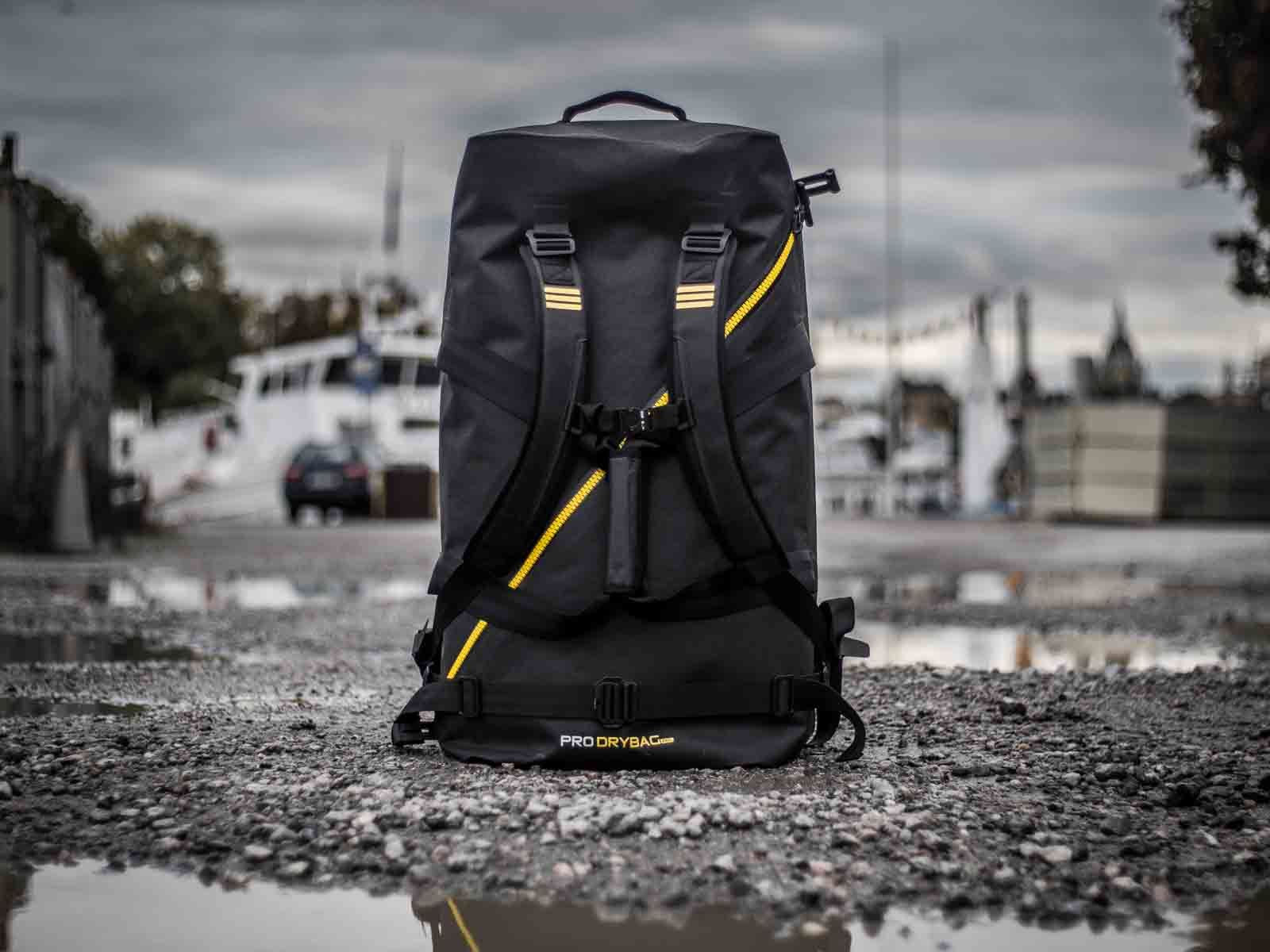 Subtech Pro Drybag 100L als wasserdichter Rucksack im Hafenumfeld. Robuste Drybag mit Rollverschluss und ergonomischem Tragesystem für Bootssport, Wasserrettung, Expeditionen, Reisen und anspruchsvolle Outdoor-Einsätze bei jedem Wetter.